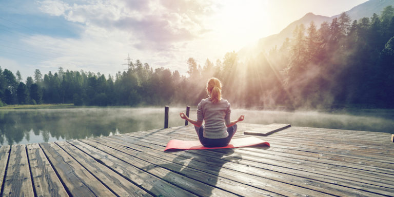 Caucasian girl exercising yoga in nature, morning by the lake in Switzerland